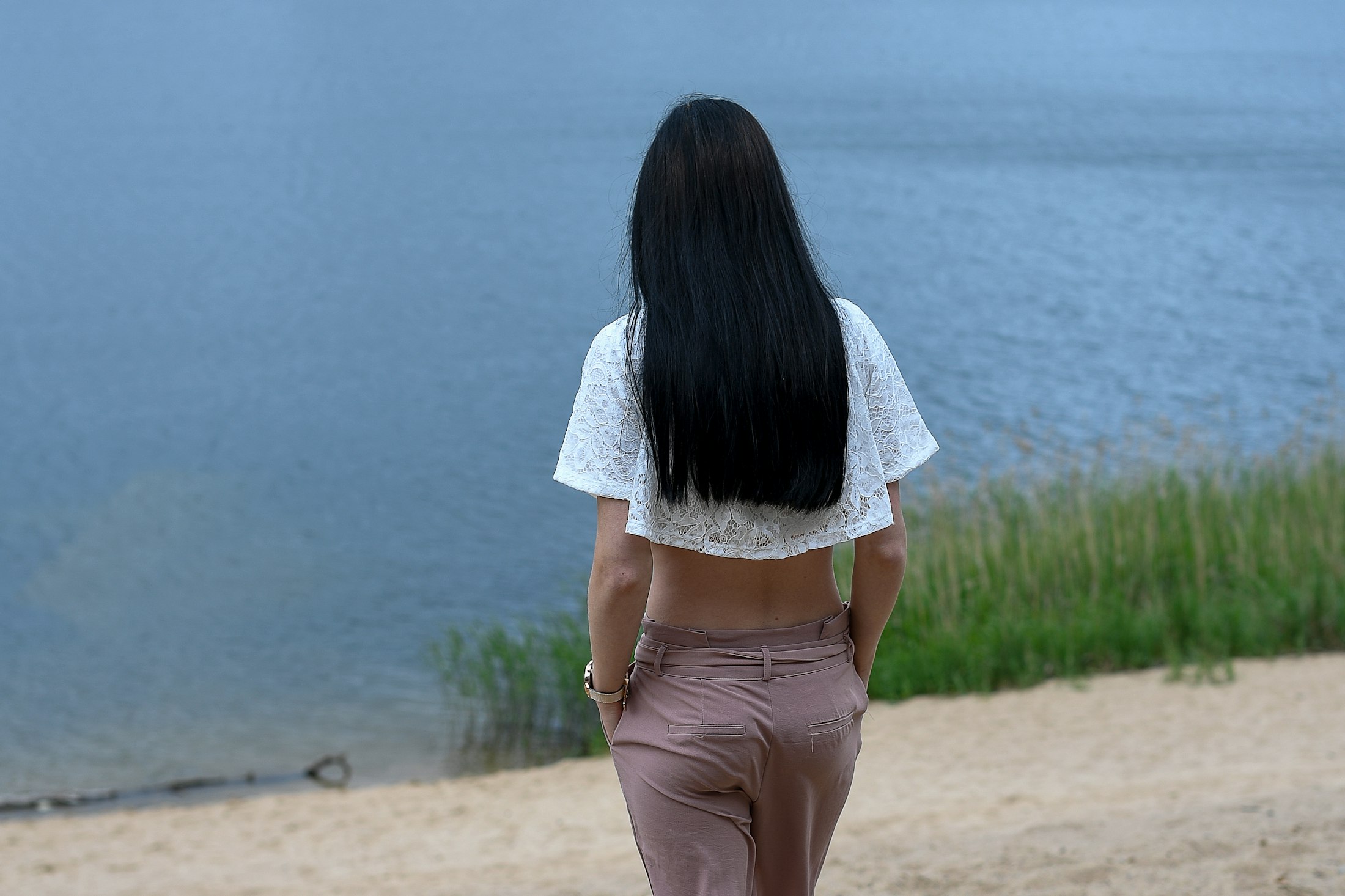水辺を歩く女性の後ろ姿と長い髪